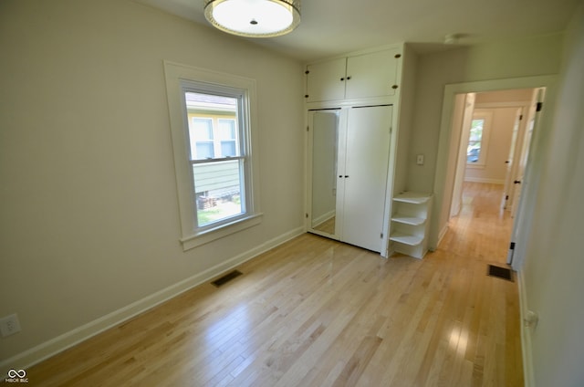 4930 Primrose Ave N, Indianapolis, IN 46205 - unfurnished bedroom featuring multiple windows, light wood-type flooring, and a closet
