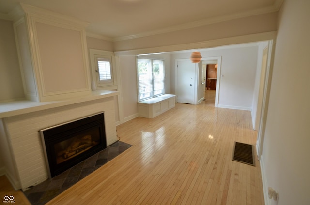 4930 Primrose Ave N, Indianapolis, IN 46205 - unfurnished living room featuring light wood-style flooring, a tiled fireplace, and crown molding