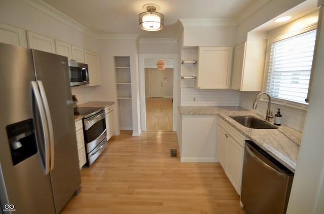 4930 Primrose Ave N, Indianapolis, IN 46205 - kitchen featuring stainless steel appliances, white cabinetry, decorative backsplash, light wood-style floors, and crown molding