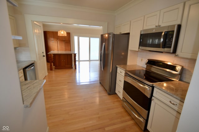 4930 Primrose Ave N, Indianapolis, IN 46205 - kitchen with appliances with stainless steel finishes, ornamental molding, decorative backsplash, light wood finished floors, and white cabinetry