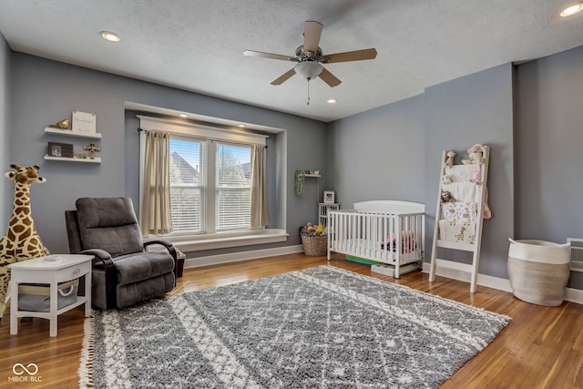 2332 Central Ave, Indianapolis, IN 46205 - bedroom featuring wood finished floors, a crib, ceiling fan, a textured ceiling, and recessed lighting