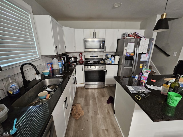 3836 N Wittfield St, Indianapolis, IN 46235 - kitchen featuring stainless steel appliances, light wood finished floors, tasteful backsplash, white cabinets, and decorative light fixtures