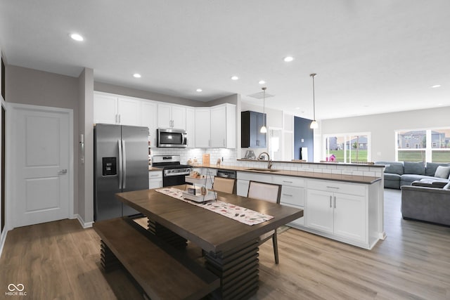 757 Carson Ln, Greenfield, IN 46140 - kitchen featuring appliances with stainless steel finishes, a peninsula, decorative backsplash, light wood-style floors, and recessed lighting