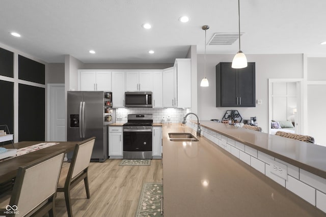 757 Carson Ln, Greenfield, IN 46140 - kitchen with appliances with stainless steel finishes, light wood-type flooring, backsplash, pendant lighting, and white cabinets