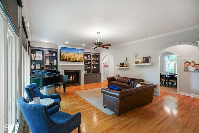 5720 Hickory Hollow Dr, Plainfield, IN 46168 - living room with arched walkways, crown molding, a ceiling fan, a lit fireplace, and wood finished floors