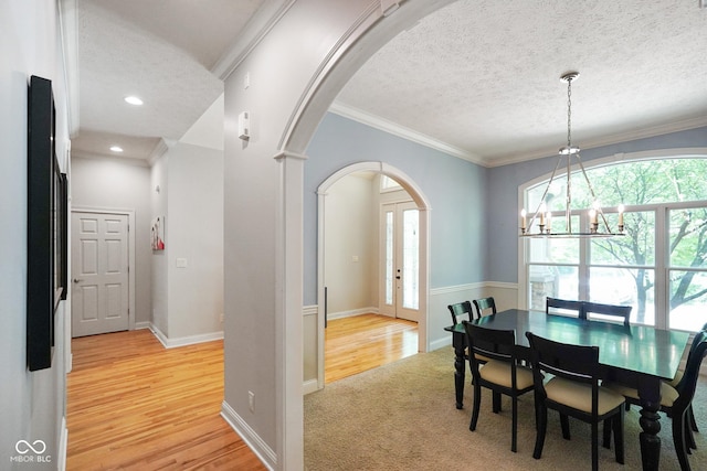 5720 Hickory Hollow Dr, Plainfield, IN 46168 - dining area with arched walkways, a chandelier, a textured ceiling, light wood-style flooring, and crown molding