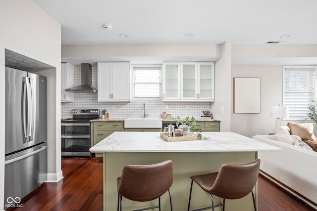 2015 N College Ave, Indianapolis, IN 46202 - kitchen with appliances with stainless steel finishes, wall chimney exhaust hood, dark wood-style floors, a breakfast bar area, and backsplash
