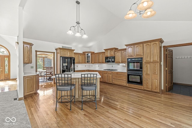 3766 Brill Rd, Indianapolis, IN 46227 - kitchen with black appliances, a chandelier, high vaulted ceiling, light wood-style flooring, and light countertops