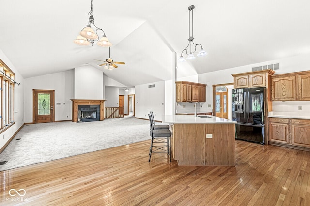 3766 Brill Rd, Indianapolis, IN 46227 - kitchen featuring black fridge with ice dispenser, a fireplace with flush hearth, light countertops, light wood-style floors, and ceiling fan