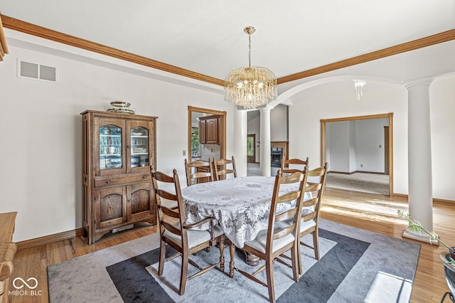3766 Brill Rd, Indianapolis, IN 46227 - dining space with ornate columns, arched walkways, wood finished floors, a chandelier, and a glass covered fireplace