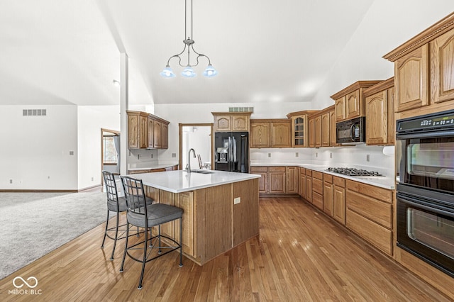 3766 Brill Rd, Indianapolis, IN 46227 - kitchen featuring black appliances, high vaulted ceiling, a kitchen island with sink, light countertops, and a breakfast bar