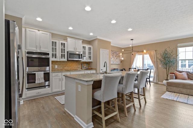 9476 Oakley Dr, Indianapolis, IN 46260 - kitchen with stainless steel appliances, open floor plan, light wood finished floors, backsplash, and white cabinets