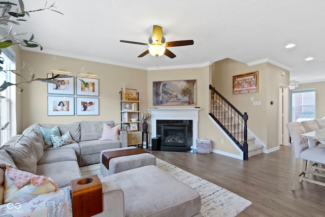 9476 Oakley Dr, Indianapolis, IN 46260 - living room with wood finished floors, a ceiling fan, stairway, a glass covered fireplace, and crown molding