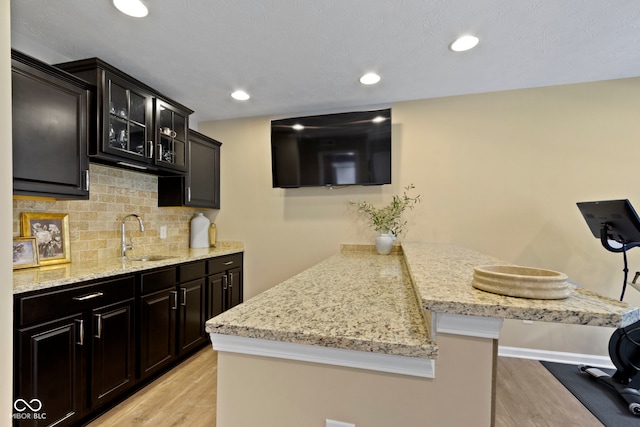 9476 Oakley Dr, Indianapolis, IN 46260 - kitchen featuring light wood finished floors, a peninsula, decorative backsplash, glass insert cabinets, and recessed lighting