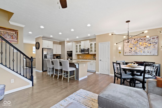 9476 Oakley Dr, Indianapolis, IN 46260 - living room featuring ornamental molding, stairs, light wood finished floors, recessed lighting, and a chandelier