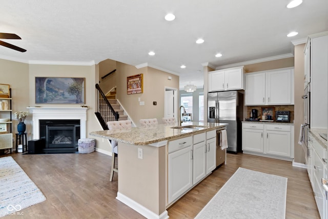 9476 Oakley Dr, Indianapolis, IN 46260 - kitchen with stainless steel appliances, a ceiling fan, a kitchen bar, light stone counters, and open floor plan
