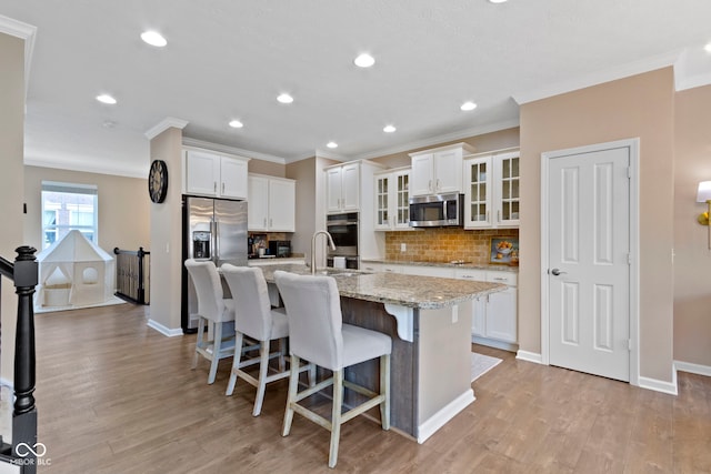 9476 Oakley Dr, Indianapolis, IN 46260 - kitchen featuring appliances with stainless steel finishes, crown molding, a center island with sink, a breakfast bar, and decorative backsplash