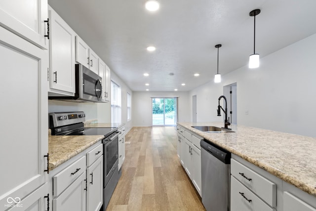 4129 Cornelius Ave, Indianapolis, IN 46208 - kitchen featuring stainless steel appliances, light wood finished floors, recessed lighting, hanging light fixtures, and white cabinets