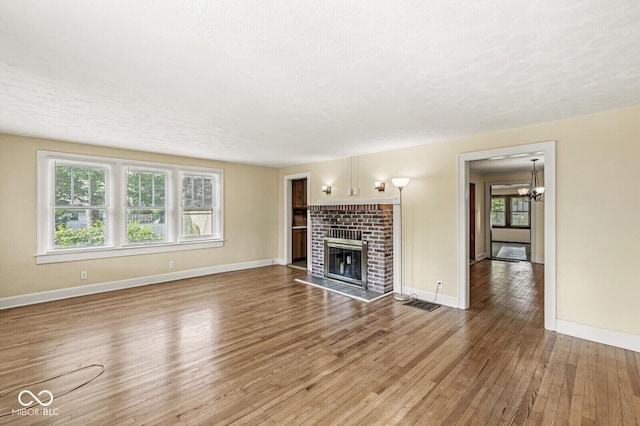 3760 Brill Rd, Indianapolis, IN 46227 - unfurnished living room featuring wood finished floors, a fireplace, and a chandelier