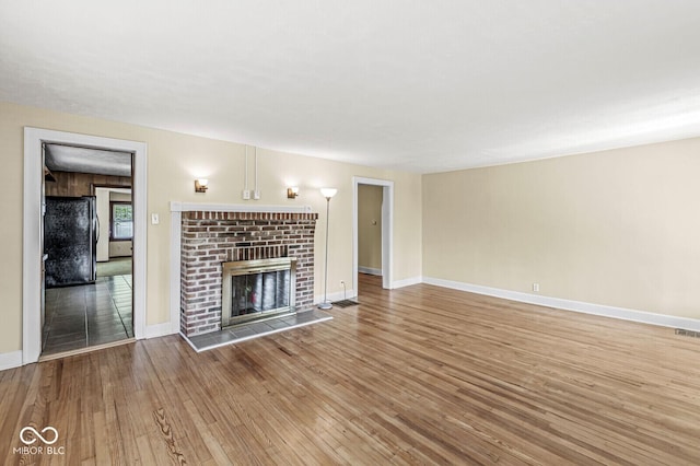 3760 Brill Rd, Indianapolis, IN 46227 - unfurnished living room featuring hardwood / wood-style flooring and a brick fireplace