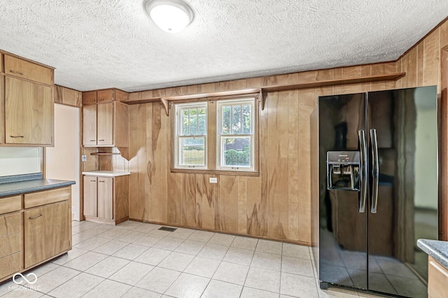 3760 Brill Rd, Indianapolis, IN 46227 - kitchen with black fridge, a textured ceiling, wooden walls, light tile patterned floors, and dark countertops