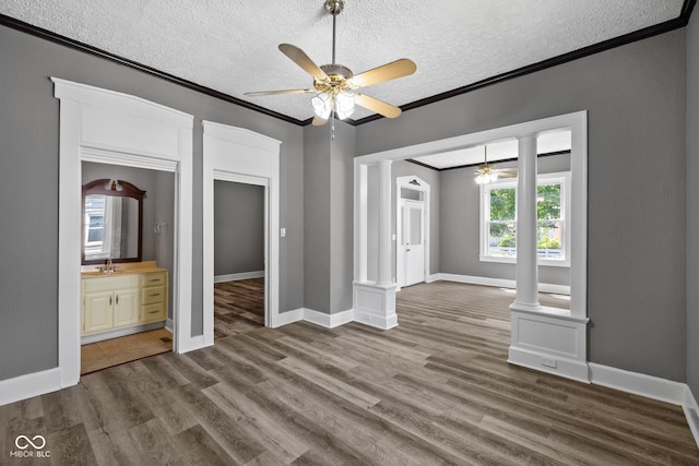 761 N Holmes Ave, Indianapolis, IN 46222 - unfurnished room with a ceiling fan, ornate columns, a textured ceiling, crown molding, and dark wood-style flooring