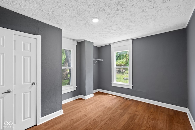 761 N Holmes Ave, Indianapolis, IN 46222 - empty room featuring a textured ceiling, healthy amount of natural light, wood finished floors, and a textured wall