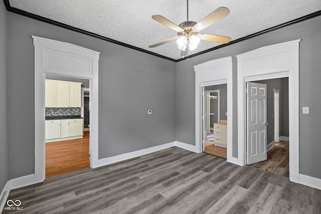 761 N Holmes Ave, Indianapolis, IN 46222 - unfurnished bedroom featuring a textured ceiling, dark wood finished floors, crown molding, and ceiling fan