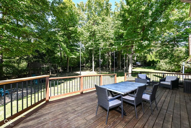 5826 Winding Way Ln, Indianapolis, IN 46220 - wooden deck featuring outdoor dining area, a playground, a lawn, and view of scattered trees