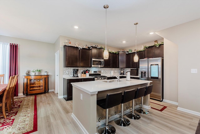 9806 Olympic Blvd, Pendleton, IN 46064 - kitchen with appliances with stainless steel finishes, light wood-style flooring, dark brown cabinets, backsplash, and light countertops
