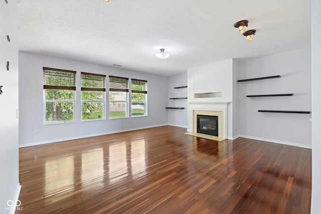 12997 Bartlett Dr, Fishers, IN 46037 - unfurnished living room featuring wood finished floors, a textured ceiling, and a fireplace with flush hearth
