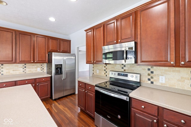 12997 Bartlett Dr, Fishers, IN 46037 - kitchen featuring appliances with stainless steel finishes, light countertops, dark wood finished floors, tasteful backsplash, and recessed lighting