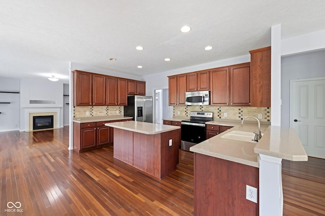12997 Bartlett Dr, Fishers, IN 46037 - kitchen featuring appliances with stainless steel finishes, backsplash, light countertops, dark wood finished floors, and a kitchen island