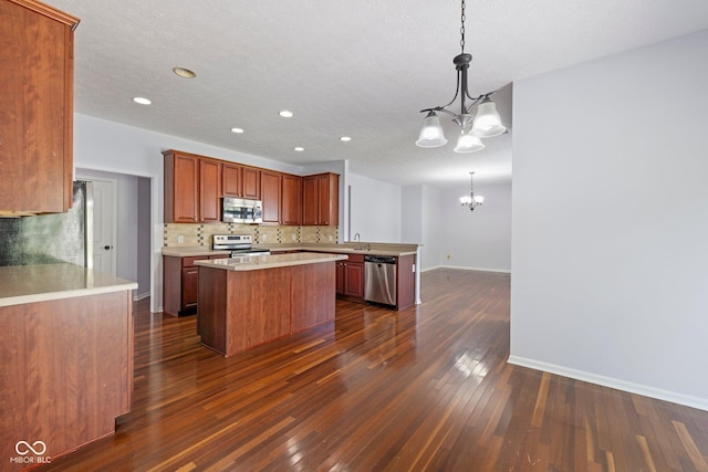 12997 Bartlett Dr, Fishers, IN 46037 - kitchen with appliances with stainless steel finishes, a chandelier, decorative backsplash, dark wood-type flooring, and light countertops