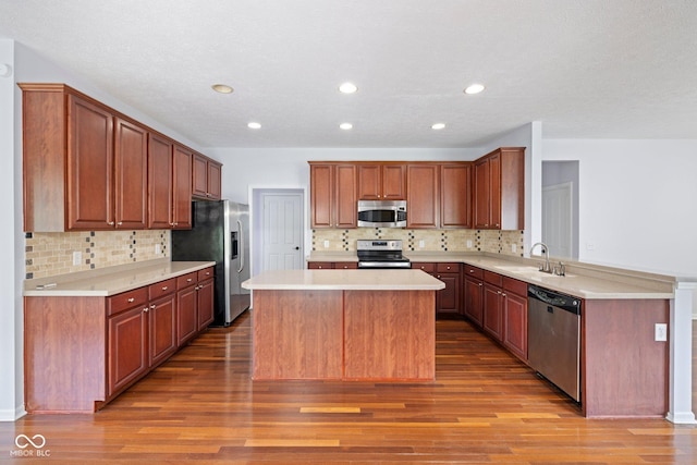 12997 Bartlett Dr, Fishers, IN 46037 - kitchen with appliances with stainless steel finishes, backsplash, a kitchen island, wood finished floors, and light countertops