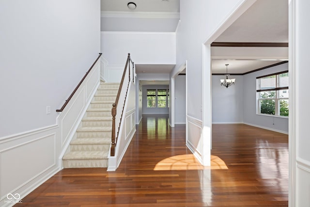 12997 Bartlett Dr, Fishers, IN 46037 - foyer with ornamental molding, wood finished floors, a chandelier, stairs, and a decorative wall