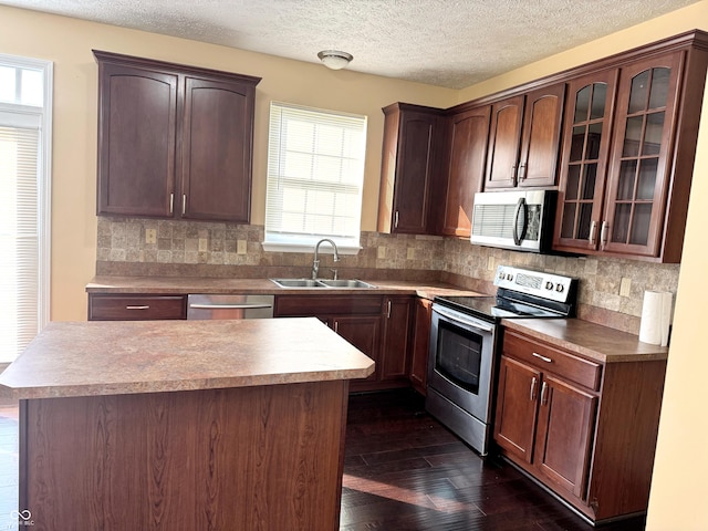 2444 Cole Branch Ct, Indianapolis, IN 46239 - kitchen featuring appliances with stainless steel finishes, backsplash, glass insert cabinets, a textured ceiling, and a kitchen island