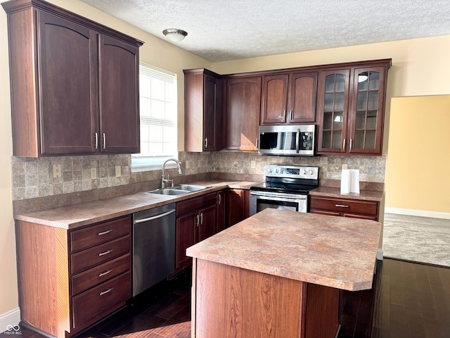 2444 Cole Branch Ct, Indianapolis, IN 46239 - kitchen featuring appliances with stainless steel finishes, dark wood finished floors, a center island, glass insert cabinets, and a textured ceiling