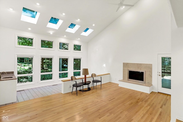 944 Briar Patch Ln, Greenwood, IN 46142 - living area featuring high vaulted ceiling, light wood-type flooring, a skylight, plenty of natural light, and a high end fireplace