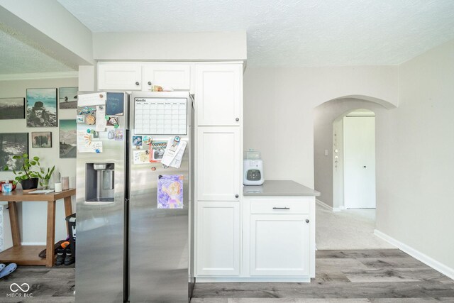 901 N Greenbriar Rd, Muncie, IN 47304 - kitchen featuring stainless steel fridge, arched walkways, light wood-style flooring, white cabinets, and a textured ceiling