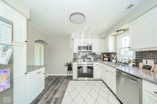 901 N Greenbriar Rd, Muncie, IN 47304 - kitchen featuring stainless steel appliances, tasteful backsplash, white cabinets, and a textured ceiling