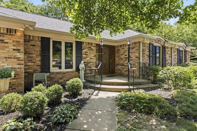 8439 Goldfinch Cir, Indianapolis, IN 46256 - doorway to property with brick siding, covered porch, and a shingled roof