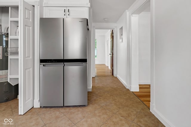 2400 Walnut St, Anderson, IN 46016 - kitchen with freestanding refrigerator, white cabinets, light tile patterned floors, and water heater