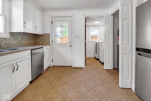 2400 Walnut St, Anderson, IN 46016 - kitchen with stainless steel appliances, tasteful backsplash, white cabinetry, washer and clothes dryer, and light tile patterned flooring