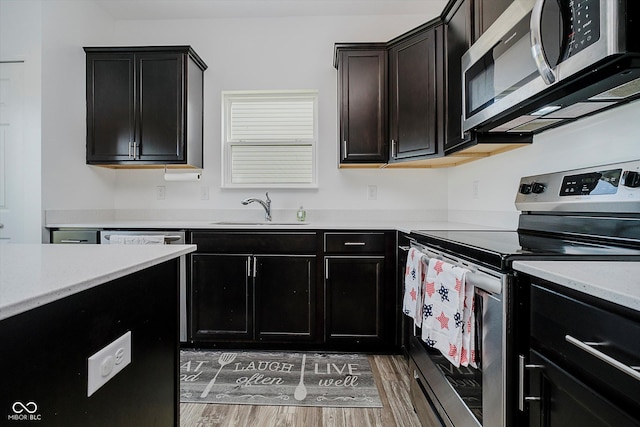 1461 Bigleaf Dr, Sheridan, IN 46069 - kitchen with appliances with stainless steel finishes, light wood-type flooring, light countertops, and dark cabinetry