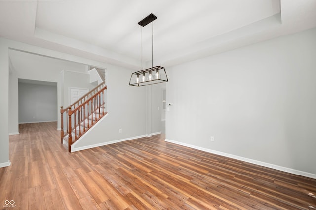 8578 Nolan Dr, Fishers, IN 46038 - unfurnished dining area with a tray ceiling, stairs, wood finished floors, and a chandelier