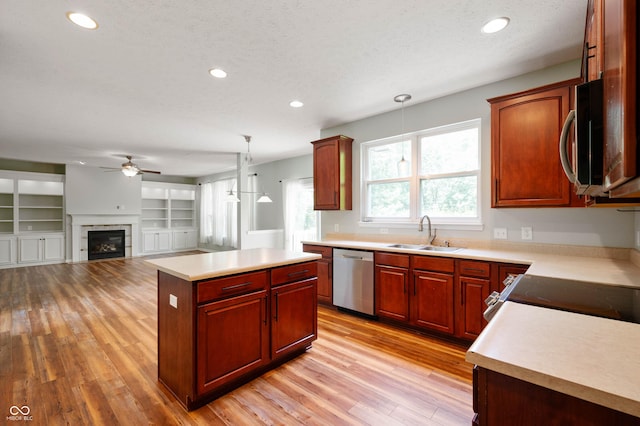 8578 Nolan Dr, Fishers, IN 46038 - kitchen featuring appliances with stainless steel finishes, a ceiling fan, light wood-type flooring, light countertops, and a glass covered fireplace