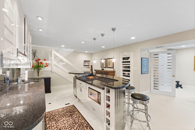 8164 Dean Rd, Indianapolis, IN 46240 - kitchen featuring a kitchen breakfast bar, white cabinets, a spacious island, dark stone counters, and recessed lighting