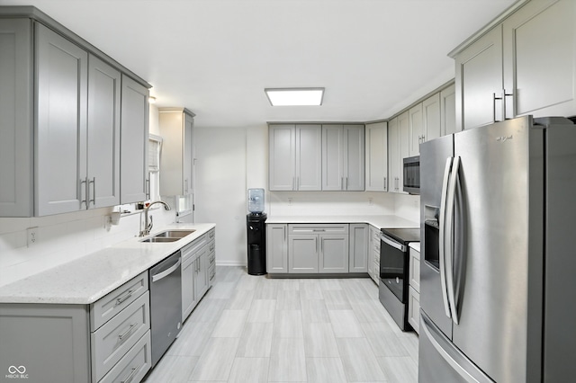8219 Bishops Ln, Indianapolis, IN 46217 - kitchen featuring stainless steel appliances, gray cabinets, light stone countertops, and tasteful backsplash