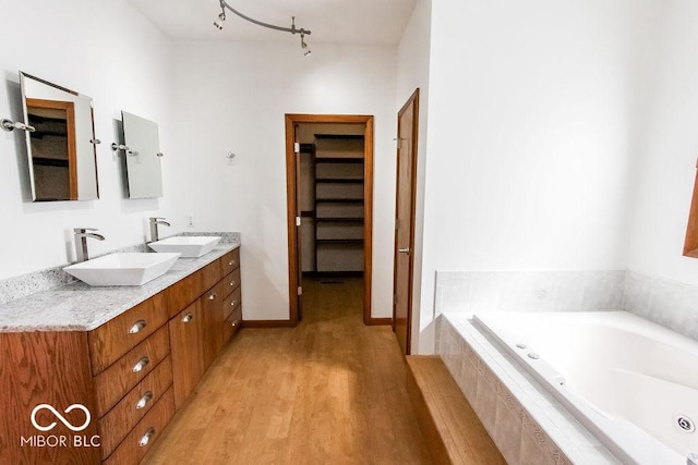 3948 S Woodfield Dr, New Palestine, IN 46163 - full bath featuring wood finished floors, double vanity, a jetted tub, and a spacious closet
